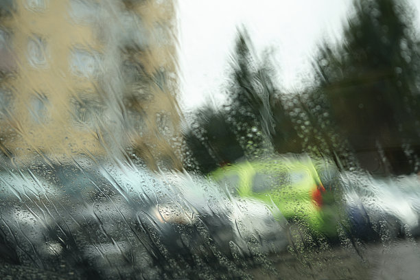 透过雨滴模糊的城市风景照片。图片下载