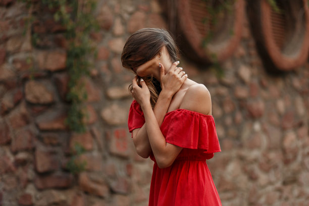 穿着红色复古裙子的时尚美丽年轻女孩，脸上有头发，在户外摆姿势。艺术照片图片下载