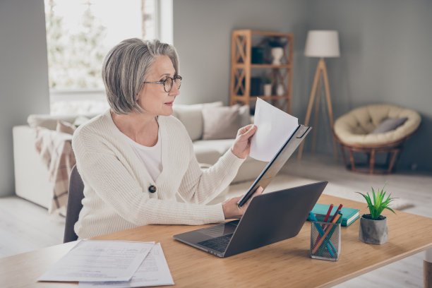 穿着白色开衫的可爱忙碌的女老板在室内房间阅读文件准备签字的照片图片下载
