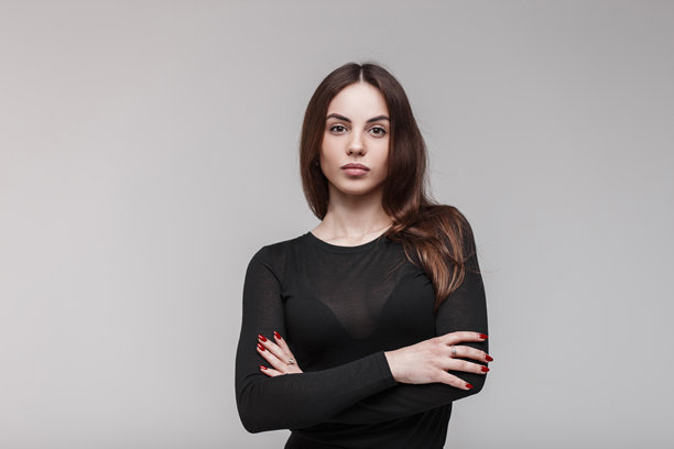 年轻性感的女性，拥有性感的嘴唇，化着自然妆，长发飘逸，穿着时尚的黑色T恤，在白色墙壁旁的室内摆姿势。可爱的时尚女孩。摄影棚照片。图片下载