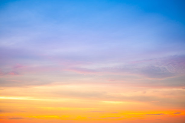 美丽的日落景观，奢华柔和的渐变橙金色云彩和阳光映照在蓝色戏剧性的天空上，完美适合作为背景，早晨、傍晚、黄昏，气候变化，横向日落照片图片下载