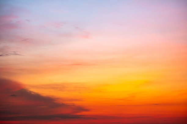 美丽的日落景观，奢华柔和的渐变橙金色云彩和阳光映照在蓝色戏剧性的天空上，完美适合作为背景，早晨、傍晚、黄昏，气候变化，横向日落照片图片下载