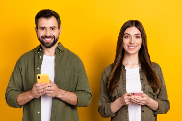 快乐的兄妹在黄色背景下用手机聊天的照片图片下载