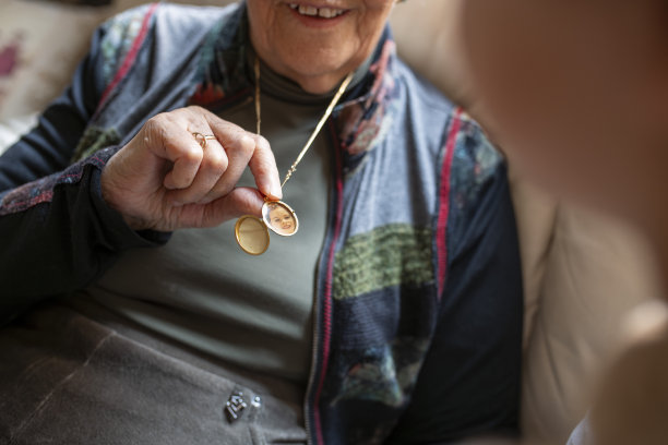 老年女性展示着带有孙子照片的金项链吊坠图片下载