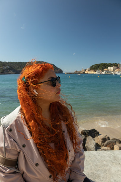 特写的竖版照片，展示一位有雀斑的女性坐在海滨长廊上，凝视着风景。图片下载