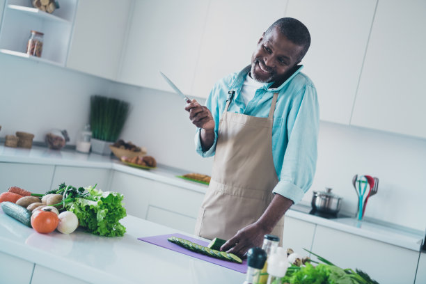 专业成熟男士在室内使用现代设备切黄瓜的照片图片下载