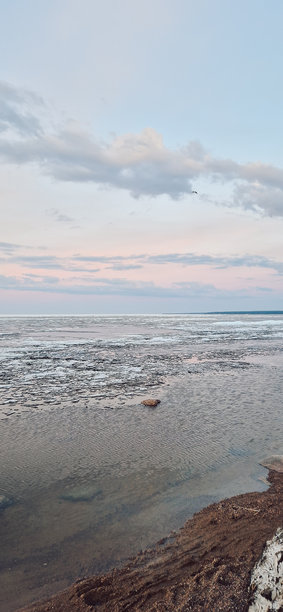 宁静的冰块在日落时分映照在平静的海洋水面上。竖版照片图片下载