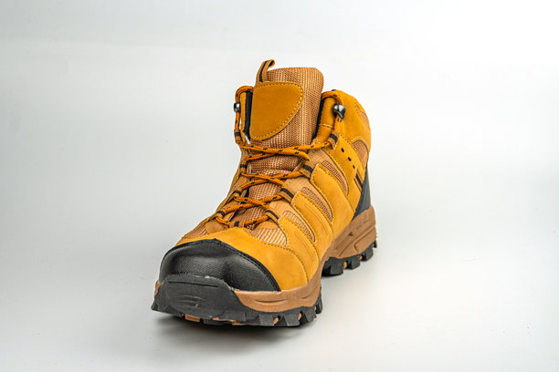 一双坚固的可调节登山靴，黄色和棕色相间，具有防滑鞋底图案，背景为中性色。这张图片展示了靴子适合户外活动如远足的设计。图片下载