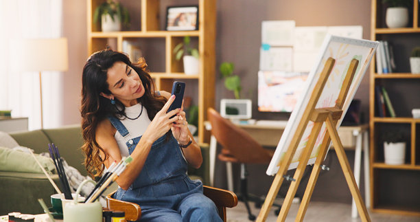 艺术家，女性和画作的照片，智能手机和艺术作品的推广，在线或社交媒体。摄影师，画家和使用手机发布的成熟人士，才华或创意在家中的画布上。图片下载