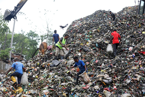 人们在不卫生的条件下工作，并在垃圾堆放场捡拾垃圾。世界环境日照片。图片下载