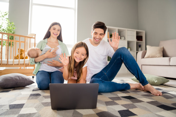 四个可爱平和的人坐在地毯上进行视频通话的全身照片图片下载