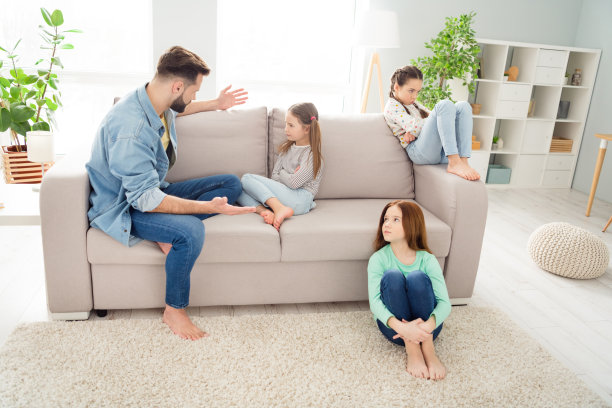 四个人的全身照片，一个男孩正在解释，旁边的女孩们手臂交叉，周末在室内的家中。图片下载