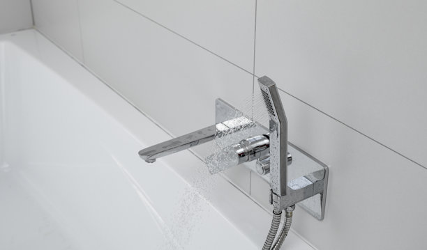 浴室内的浴缸用白色硅胶固定，配有干净的铬制水龙头和淋浴头图片下载