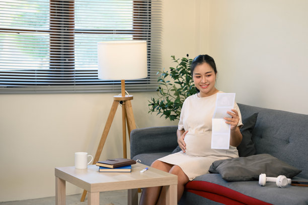 快乐的孕妇欣赏超声波照片，轻轻抚摸着自己的肚子图片下载