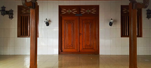 这张图片展示了一个对称的建筑细节，中央是一个木质双开门，两侧是设计相似的窗户。墙壁铺有白色瓷砖，地面是浅色瓷砖，反射出一些光线。图片下载