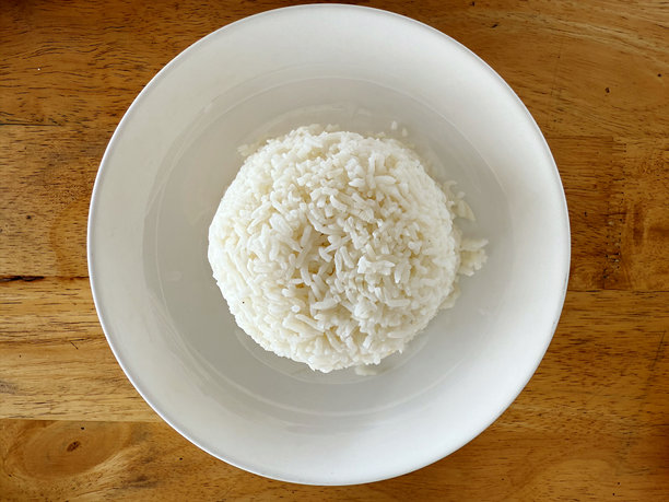白色盘子里的米饭放在木桌上，库存照片图片下载
