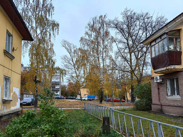 带有庭院、树木、围栏的两层公寓楼，远处是九层楼的建筑。苏联风格建筑。秋天。俄罗斯。下诺夫哥罗德。斯特列尔科瓦街。2024年10月。照片。图片下载