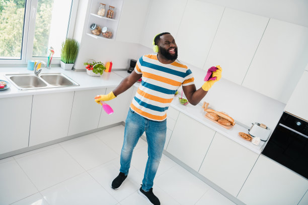 全景高角度照片，兴奋的积极人士在室内厨房里手持喷雾，享受播放列表中的歌曲。图片下载