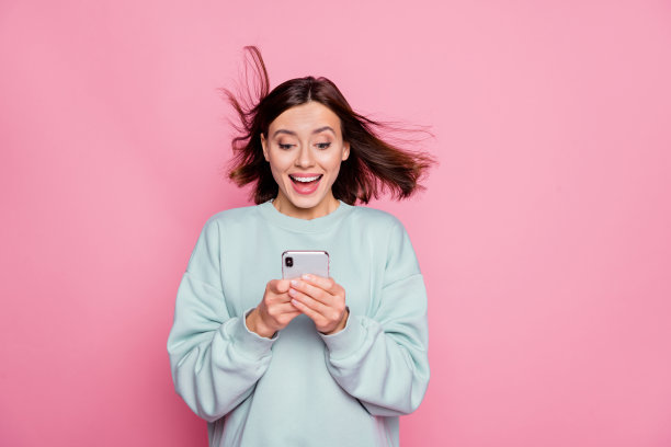 年轻漂亮女孩在粉色背景下，因好消息而评论流行应用下载的照片图片下载