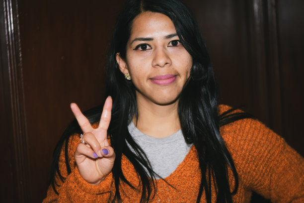 用户生成内容。复古风格的照片，由真实的人拍摄，女性向镜头做出安波尔和和平的手势。图片下载