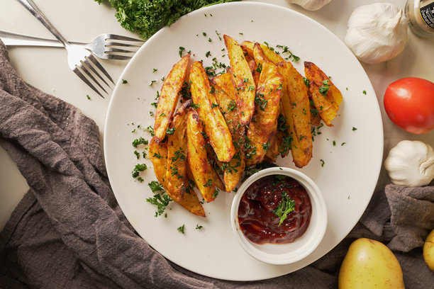 从上方拍摄的烤土豆，撒上红椒粉和大蒜，点缀新鲜香菜和浓郁番茄酱，这是一道令人无法抗拒的自制美食，刚从烤箱中取出。垂直照片。图片下载