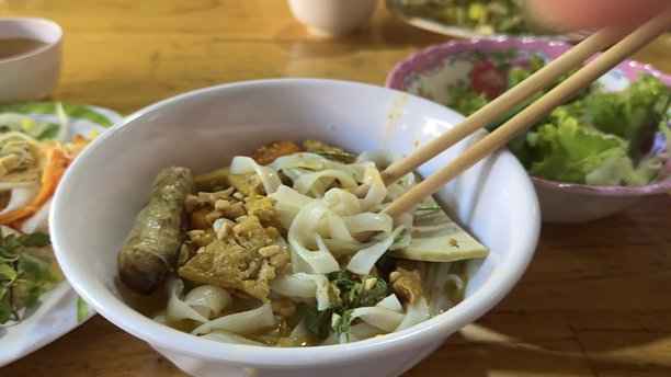 卧室阳台的垂直照片，女人正在享用猪肉、丸子、脆皮猪肉、罗勒叶和蔬菜的浓汤面。这是泰国传统而著名的街头美食。图片下载