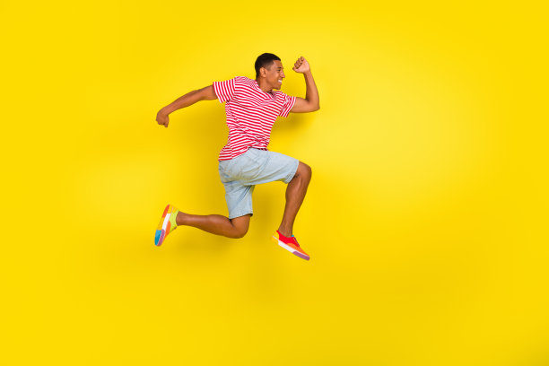 全身侧面照片，男孩跳跃奔跑，穿着红色条纹衣服，背景为明亮的色彩，展现季节购物的优惠。图片下载