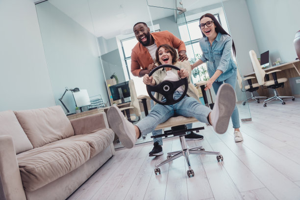 现代工作空间中，积极的女CEO和男市场营销人员放松休息，玩网络科技竞速游戏的全身照片。图片下载