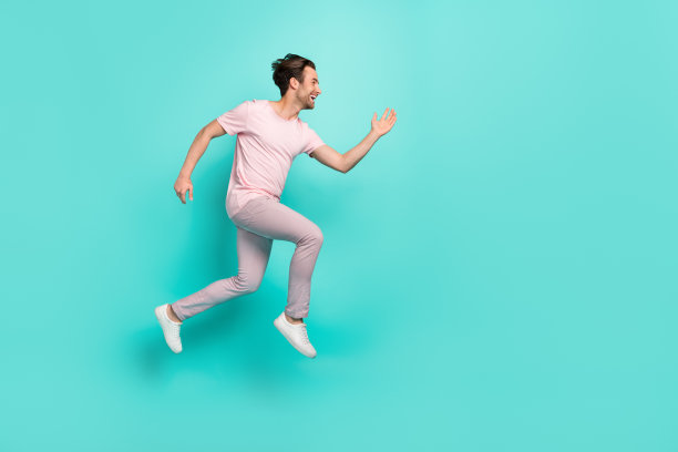 年轻男孩穿着运动服的全身侧面照片，活力四射，匆忙的神情，背景为清新的青色，周围空间空旷。图片下载