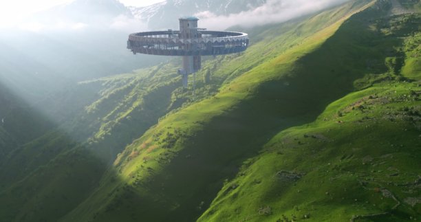 这张照片展示了一艘明亮的外星飞船在阳光明媚的白天低悬在郁郁葱葱的山丘上。图片下载