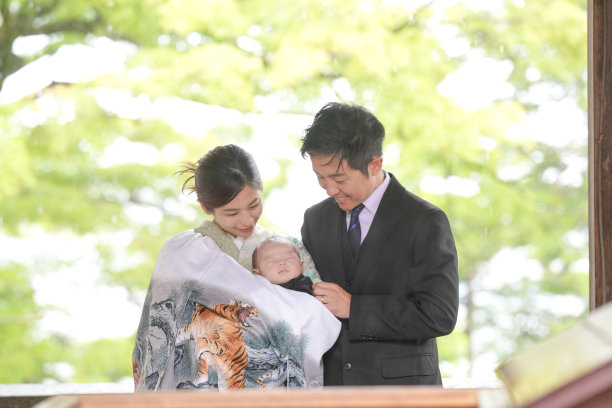 在五月的春天，一位穿着袴的一个月大的日本婴儿被一位身穿西装的男子抱着，旁边是一位穿着和服的母亲，两人都是二十多岁，正在摆姿势拍摄家庭照片。图片下载
