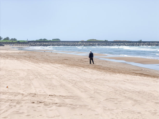 在五月的日本海，一个七十多岁的日本男子在微风拂面的春日里独自漫步在海滩上，航拍照片展现了波浪和宁静的孤独。图片下载