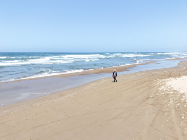 在五月的日本海，一个七十多岁的日本男子在微风拂面的春日里独自漫步在海滩上，航拍照片展现了波浪和宁静的孤独。图片下载