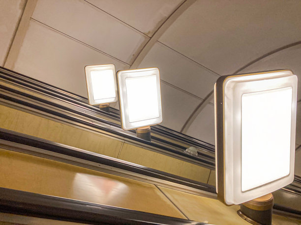 一张电梯的 candid 照片，展示了两个上升的台阶，每个台阶上都有广告或信息。照片强调了向上的视角，并在上方展示了额外的广告。图片下载