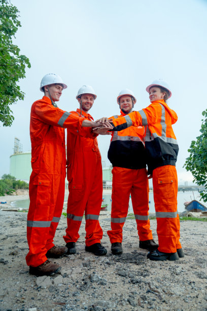 一群石化工人或技术人员在工厂储罐前站立并手拉手的竖版照片。图片下载