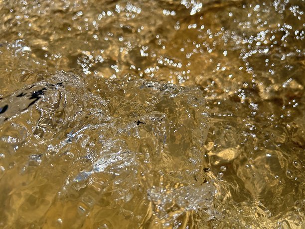 小溪中水的特写。聚焦于小溪水面的一张特写照片。光线的反射在流过自然岩石的水面上闪烁。图片下载