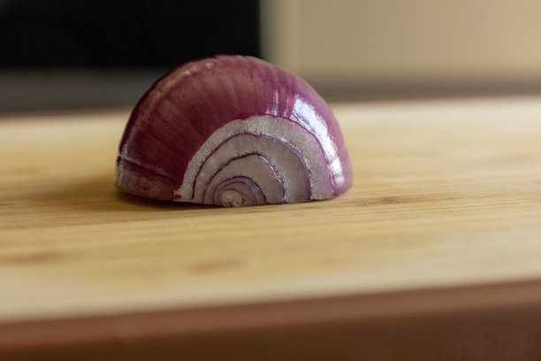 半个紫洋葱静静地放在木板上，特写照片。图片下载