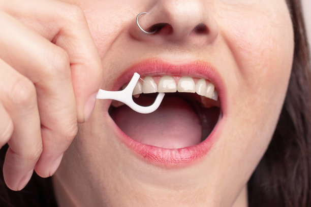 女性使用牙线棒清洁牙齿，刷牙。健康牙齿和自我护理的概念特写照片图片下载