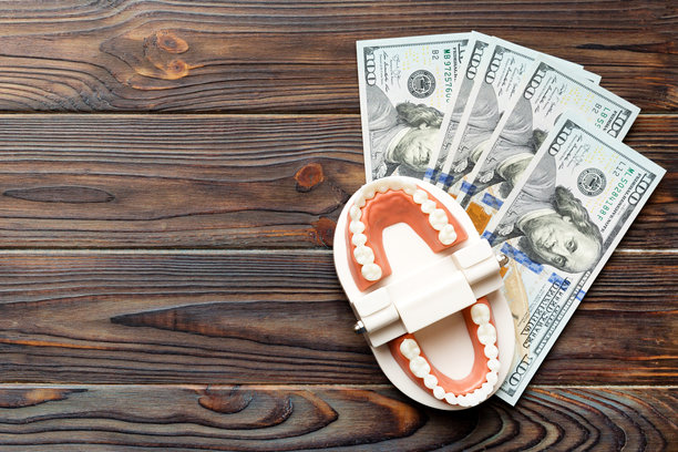 特写的人类下颌模型，白色牙齿和美元钞票。牙科概念照片。义齿。假牙的俯视图，留有空白空间。图片下载