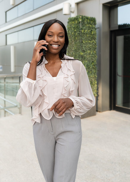 微笑的非洲裔美国女商人在办公室外走动并打电话的竖版图片图片下载