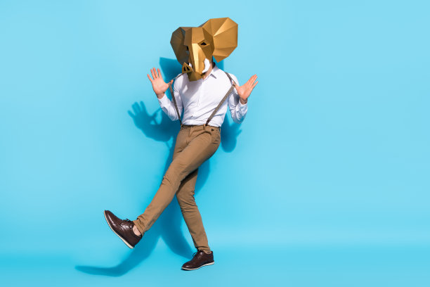 年轻男舞者的全身侧面照片，穿着独特的服装，背景为蓝色。图片下载