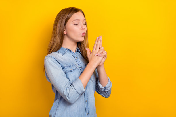 可爱的小金发女孩手持玩具枪，穿着牛仔服，背景为鲜艳的黄色。图片下载