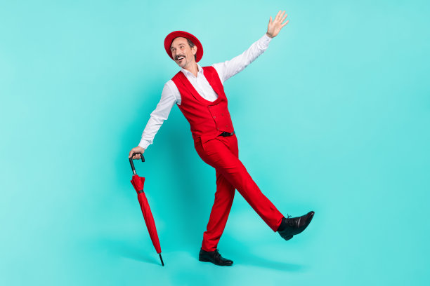 成熟快乐的男性全身侧面照片，享受散步，修饰得体，背景为青绿色。图片下载