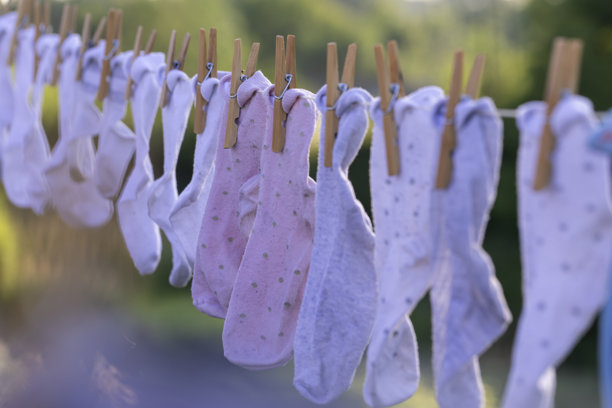 新洗的袜子挂在绳子上，使用天然木质夹子，完美的概念照片，适合育儿、洗衣日、可持续发展和日常家庭生活。图片下载