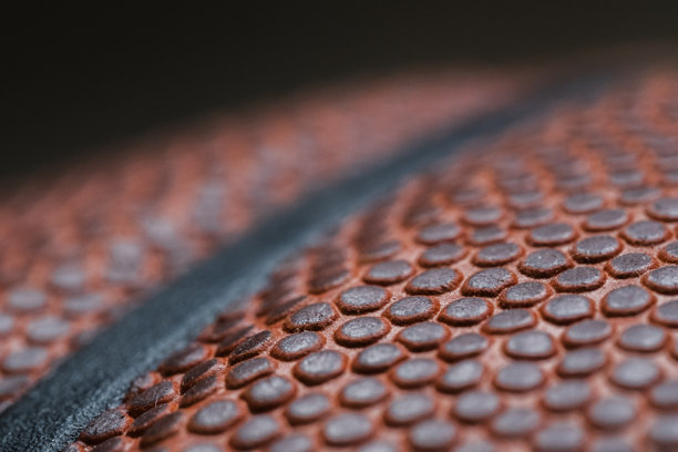 特写宏观照片，展示一颗篮球上有一条黑色橡胶条，背景为黑色。图片下载