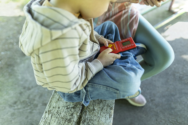 男孩坐在长椅上玩游戏。特写照片图片下载