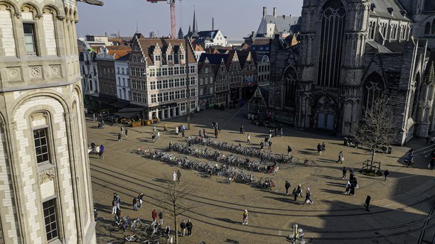 阳光明媚的日子里，根特的Korenmarkt鸟瞰图，展现了历史建筑、圣尼古拉斯教堂和热闹的广场，广场上有许多自行车，明亮的城市风景，展示了弗拉芒建筑和城市生活，适合旅行和文化遗产主题的照片内容。图片下载