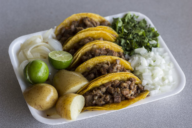 这张图片展示了一盘美味的肉馅塔可，配有新鲜的香菜、洋葱、青柠和土豆，令人垂涎欲滴，带来令人满意的美食体验。图片下载