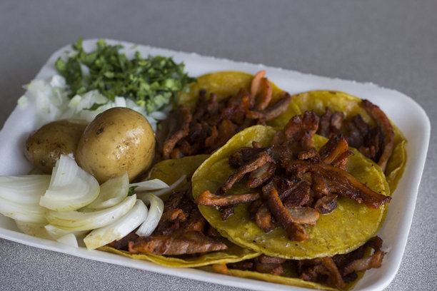 这张图片展示了一盘色彩鲜艳的阿尔帕斯托塔可，配有新鲜的香菜、洋葱和土豆，突显了传统墨西哥美食的精髓。图片下载