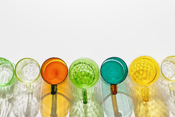 色彩斑斓的眼镜图案，白色背景上有阴影和阳光反射，创意现代设计的俯视图，彩色玻璃杯用于饮料和鸡尾酒，夏季派对概念。时尚照片图片下载